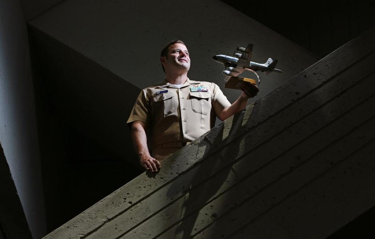 Hurricane Hunter Commander Justin Kibbey pilots the P-3 airplane that flies into hurricanes. Kibbey is currently the director of the building at the the National Oceanographic and Atmospheric facility in Virginia Key. He holds a model of the P-3 that he flies.