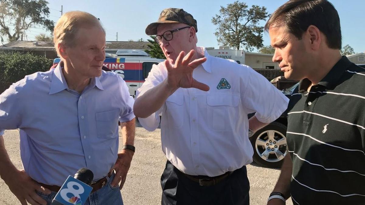 U.S. Sens. Bill Nelson, left, and Marco Rubio, right, talk with Michael Sparks, CEO of Florida Citrus Mutual, an industry group, Sept. 13 in Lake Wales. The senators toured an orange grove to assess the scope of damage to the state’s iconic crop after Hurricane Irma.