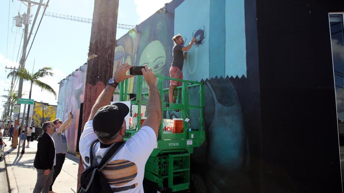 Visitors to Wynwood stop to photograph artist Seth Globepainter as he puts the finishing touches on his mural on the side of the Wynwood Kitchen & Bar on Dec. 4, 2017.