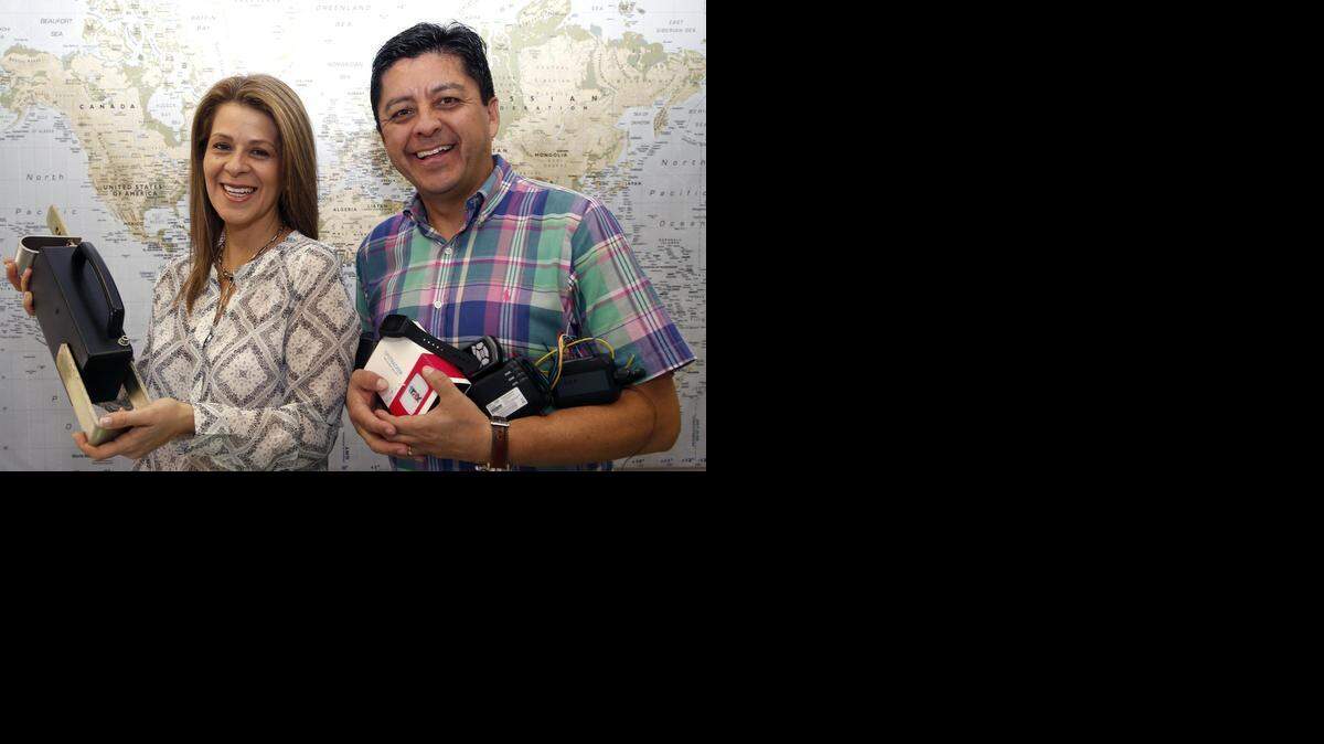 
Diego Arteaga and his wife, Francis, hold tracking devices that DF International Group exports. The company specializes in wholesaling GPS systems to use on vehicles, motorcycles, boats and commercial trucks.



