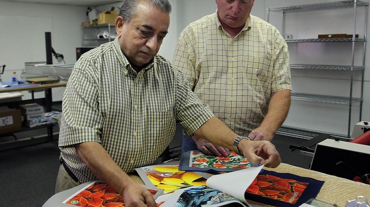 Abbas A. Sadriwalla, left, who heads Liquiguard Technologies in Fort Lauderdale, with David B. Kew, marketing and technical director. They’re looking through samples of work produced with the company’s Graphixon technology.
