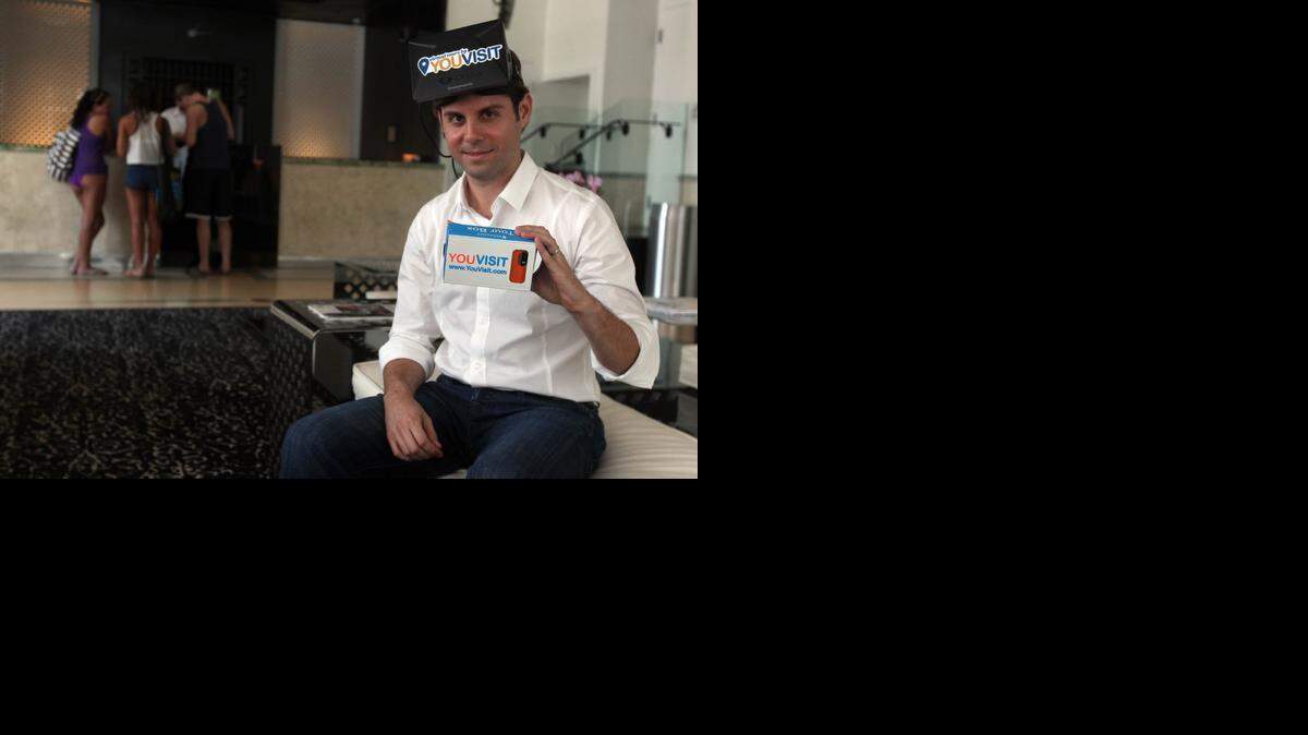 
YouVisit CEO Abi Mandelbaum poses in the lobby of the Dream Hotel in Miami Beach with his virtual reality headset and cellphone that can to used to view YouVisit tours. YouVisit, which was started as an online college tour company, is expanding into many industries including hospitality and travel. 
