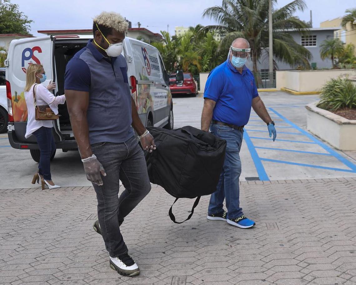 On April 13, 2020, Osvaldo Prez, right, Presidente Supermarket manager, and baseball free-agent Yasiel Puig, center, carry a thermo bag full of meals for healthcare workers at Dr. Rafael A. Peñalver Clinic, 971 NW Second St., in Miami. It’s part of The Jackson Health System.