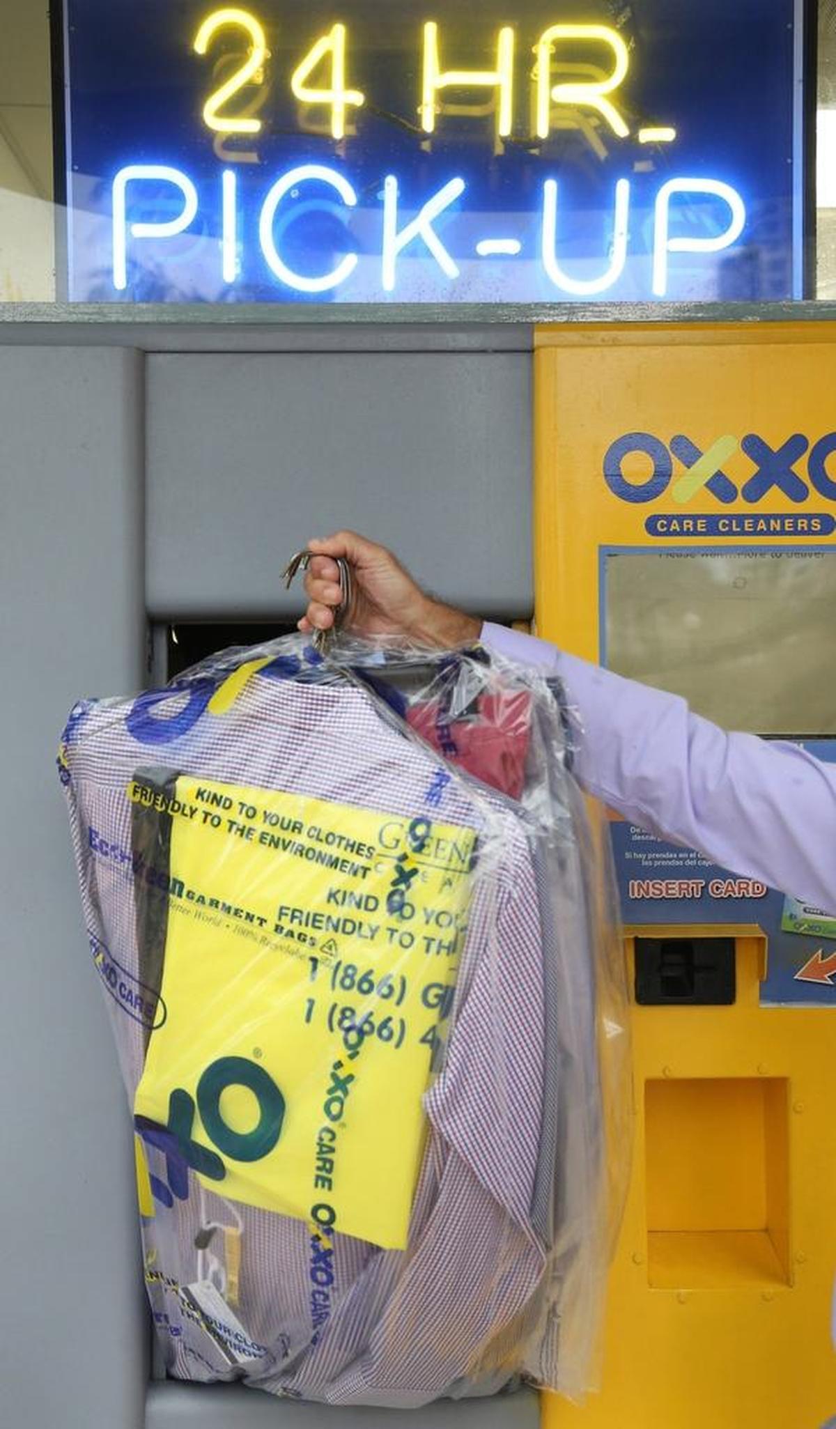 Salomon Mishaan, president of OXXO Care Cleaners, simulates a drop-off or pick-up at his business.