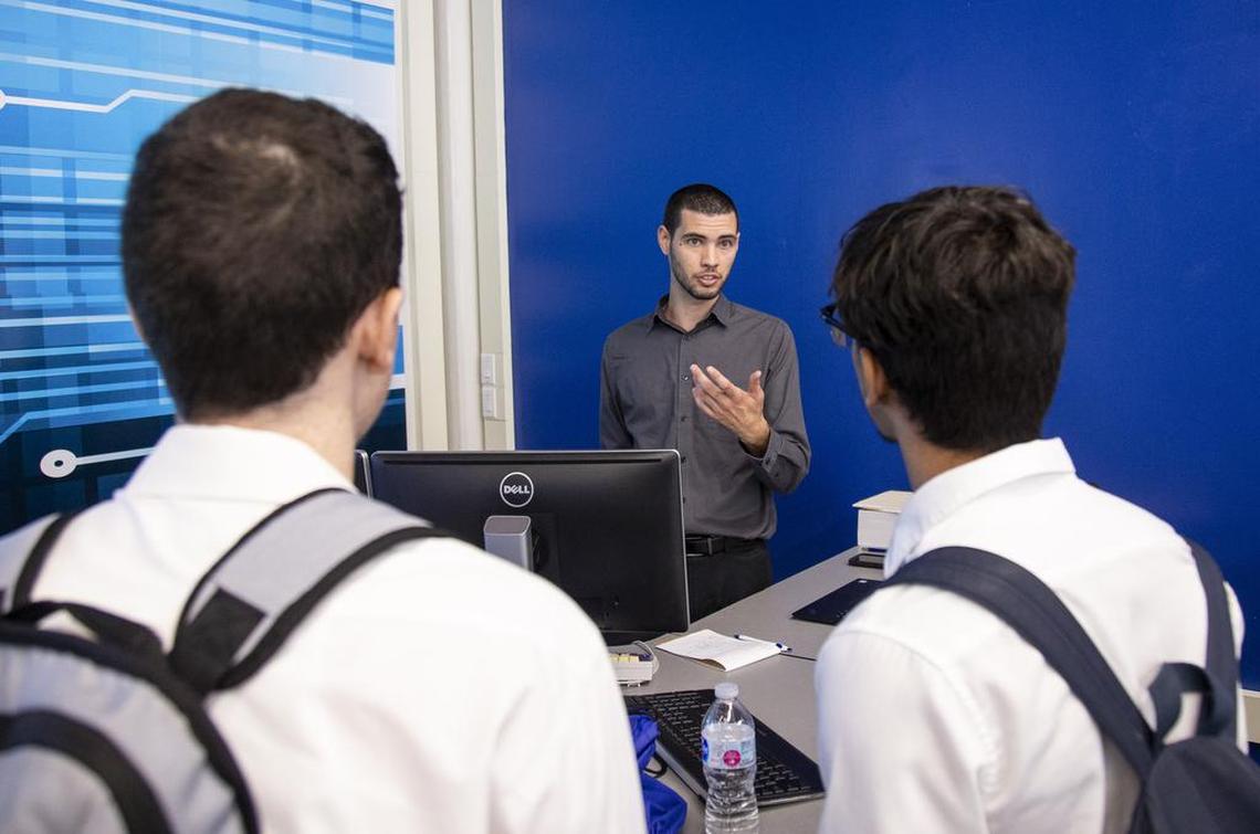Franklin Mesa Jr., lead instructor at the Cybersecurity Center of the Americas at Miami Dade College - Wolfson Campus in downtown Miami talks to students Alan Lozano, 18, left, and Angel Hidalgo, 18, after class on July 15.