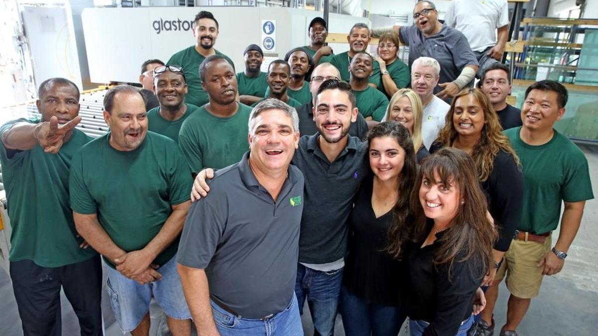 Larry and Page Giacin with their children Tyler and Brooke (center), and their employees in the manufacturing area at Shower Doors & More in Fort Lauderdale.