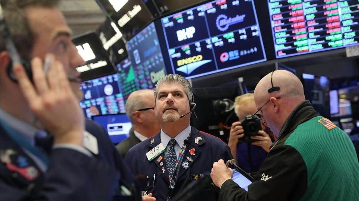 Traders work on the floor of the New York Stock Exchange on Wednesday, when The Dow Jones industrial average closed above 26,000 for the first time.
