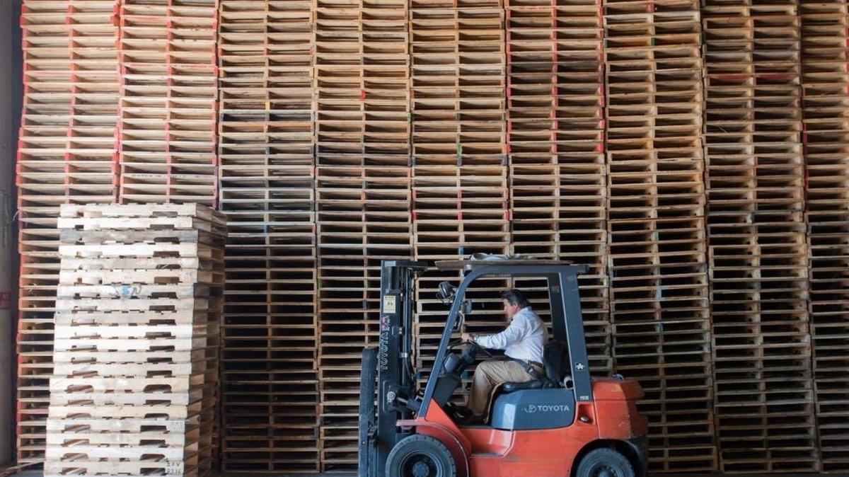 Rigoberto Lesteiro Jr., president and founder of Tropical Pallets, moves a stack of the shipping platforms inside his warehouse in Allapattah.