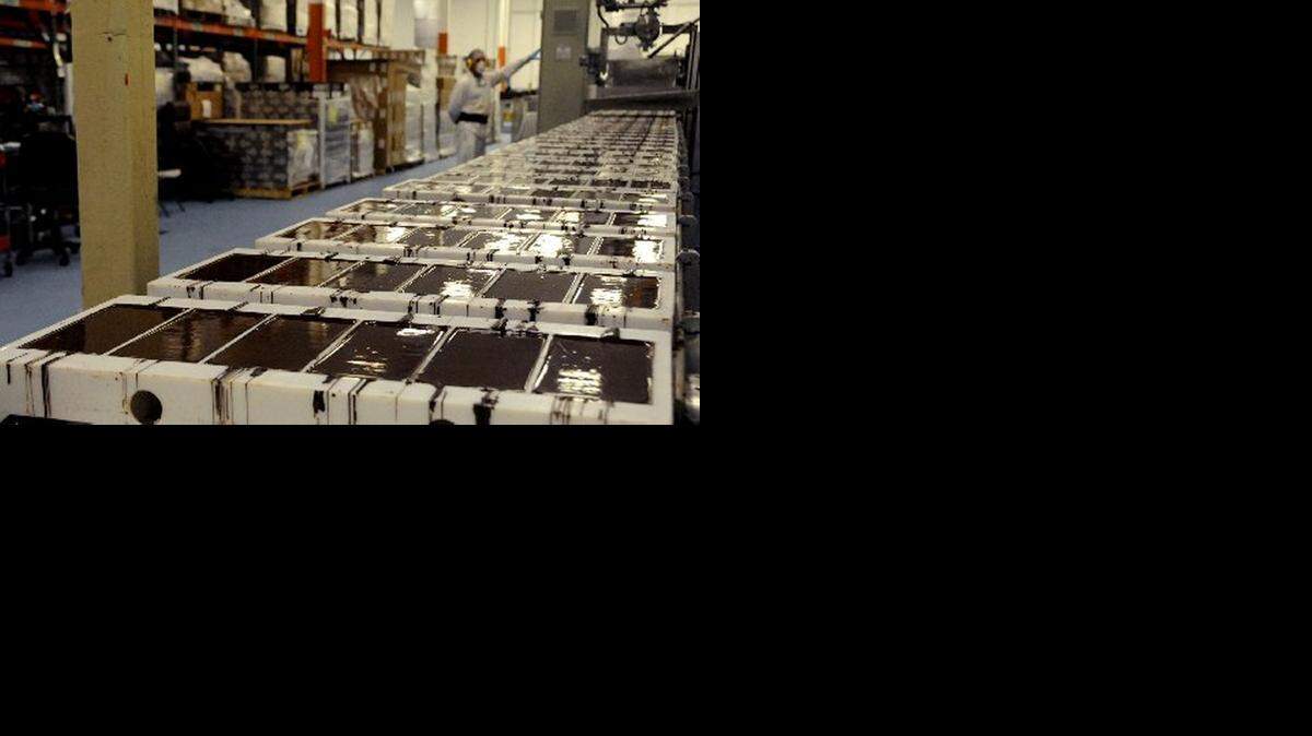 
CHOCOLATE CHILLIN’: A batch of warm chocolate sitting in trays at the Tierra Nueva factory is vibrated to remove air bubbles as it cools. After cooling, it will move to the wrapping and packing section. The company sold 1.4 million pounds of chocolate last year to customers in the U.S. and overseas.
