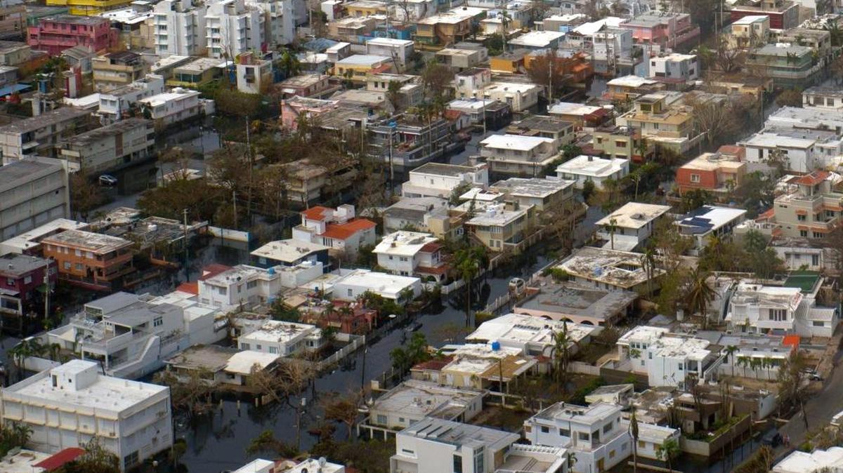 This aerial photo shows buildings still surrounded by flood water, a week after the passing of Hurricane Maria, in San Juan, Puerto Rico, on Sept. 27, 2017. Lloyd’s of London lowered its initial estimate of net insurance claims on the island. Most insured buildings held up fairly well. The problem: Large swaths of Puerto Rican real estate carried no insurance.