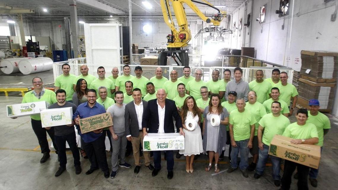 South Florida Tissue Paper Co. employees gather for a group photo on Nov. 4 inside the family-owned business’ 101,000-square-foot facility in Miami Gardens. At center, CEO Juan Corzo Sr. holds a box. He is flanked by his son, company Vice President Juan Corzo Jr., and by his wife, Logistics Manager Clara Crocker. The business is at 5590 NW 163rd St.