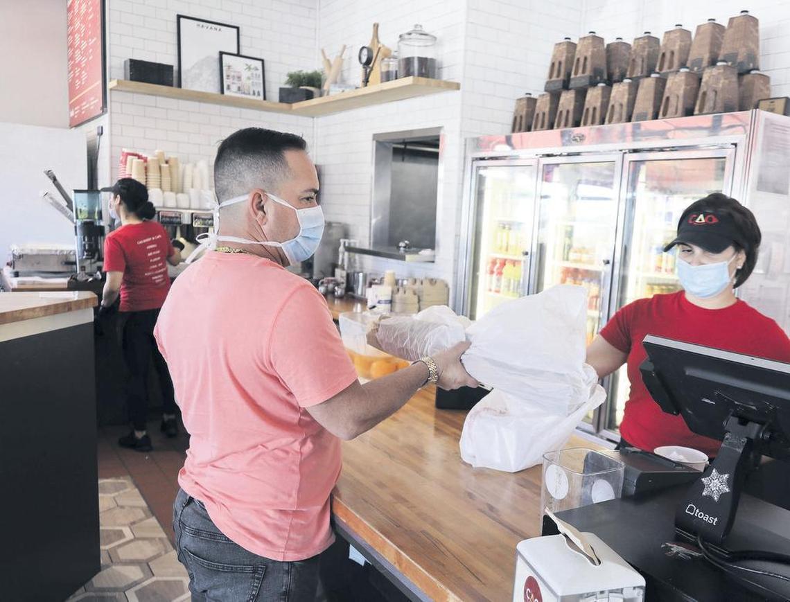 Employee Jennifer Ramos, right, hands a customer a loaf of free Cuban bread at CAO Bakery at 7830 Coral Way.