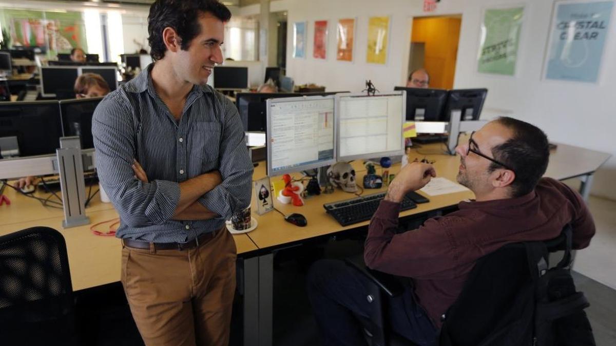 CEO Luis R. de la Vega of ProTranslating, left, speaks with translator Elian E. Degen Canelón at the office in Coral Gables.