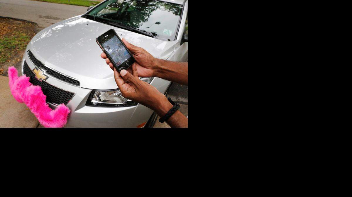 
CAR AT YOUR SERVICE: A Lyft driver closes out a trip on his smart phone. Lyft started service in Miami in late May.
