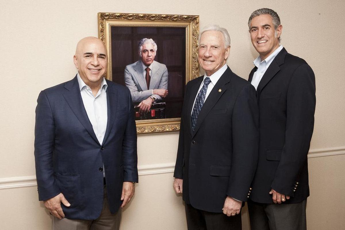 NewsLink's Ray Kayal Jr., right, who runs a business started by his grandfather, Mitchell Sirgany (in portrait), is shown with his father, Ray Kayal Sr., and business partner, Chris Korge.