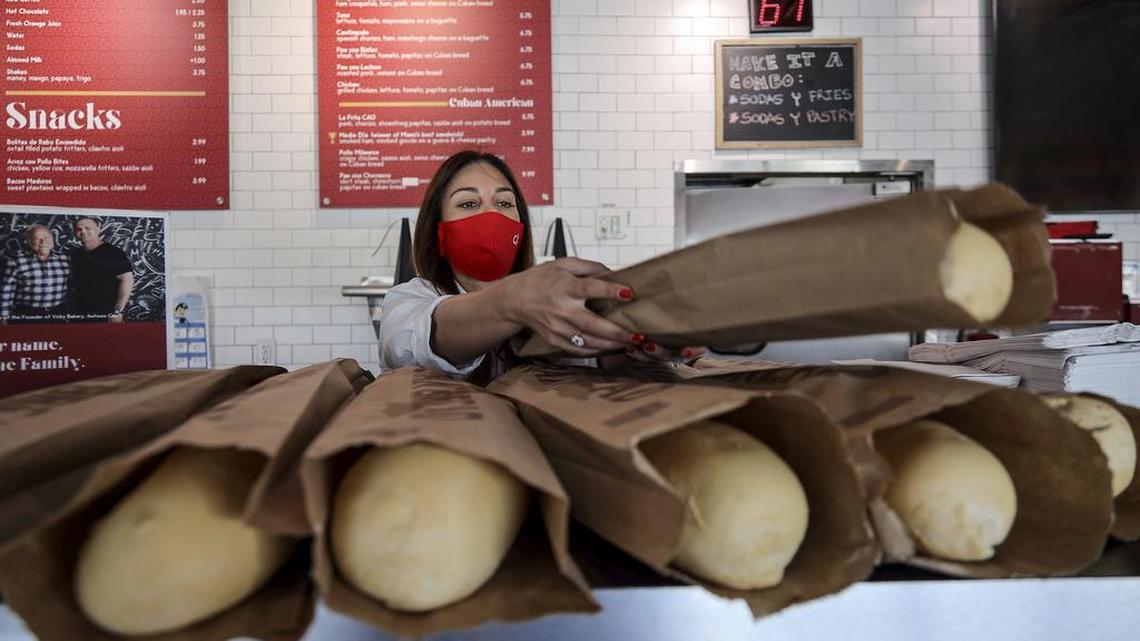 Yvette Cao, who operates CAO Bakery with her husband, sorts out bread on the counter top to be given to customers on Monday, April 27, 2020. CAO bakery have been providing a free loaf of Cuban bread to anyone who visits their stores - customers and non-customers - every Monday since the middle of March. So far, they have given away more than 500 loaves free.