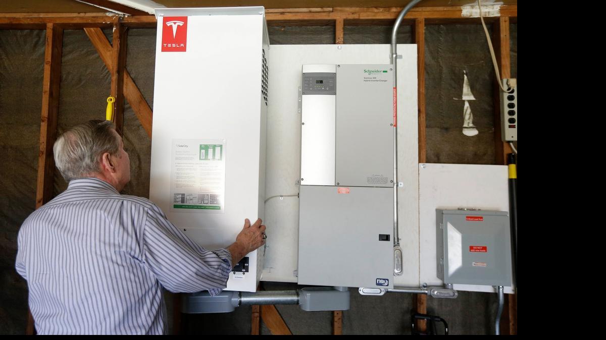 
In this April 20, 2015 photo, David Cunningham shows a prototype Tesla battery system that powers his Foster City, Calif. home. Cunningham installed a Tesla battery late last year to pair with his solar panels as part of a pilot program run by the California Public Utilities Commission to test home battery performance.
