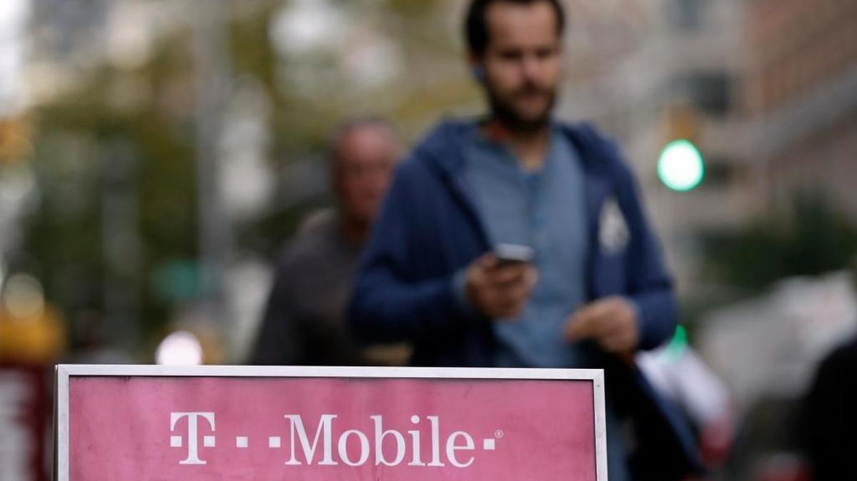 This Oct. 14, 2015, file photo, shows people passing a T-Mobile store, in New York.