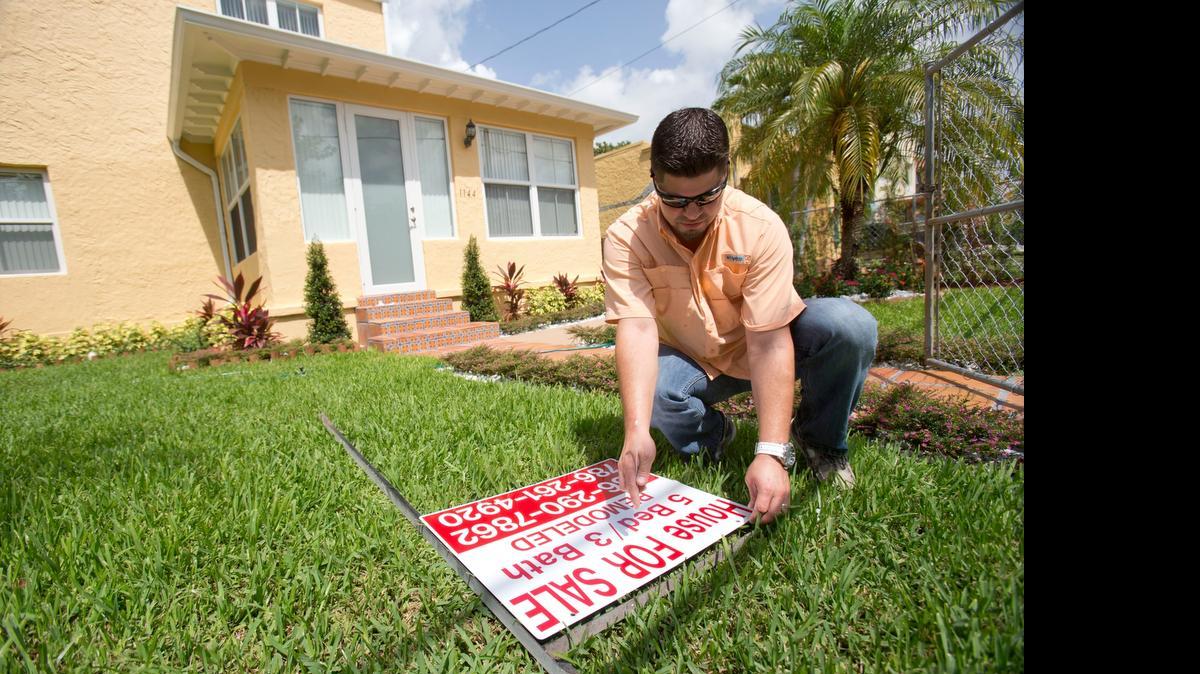 
In this April 24, 2015 photo, Robert Almirall, director of marketing and special assets coordinator for Mederos & Associates Real Estate Inc., prepares to put up a sign in front of a home in the Shenandoah neighborhood of Miami. The National Association of Realtors releases existing home sales for April on Thursday, May 21, 2015. 
