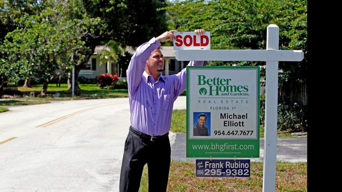 
Fort Lauderdale Realtor Michael Elliott puts a SOLD sign on the shingle outside a home in Wilton Manors that sold after a short time on the market. 
