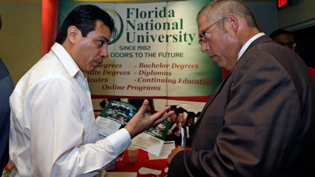 
Luigi Valdivieso, left, talks about job opportunities to Richard Solano at a job fair in Miami Lakes, on July 15, 2015. A new report says Florida is one of the worst state’s in the nation when it comes to paying unemployment benefits. 
