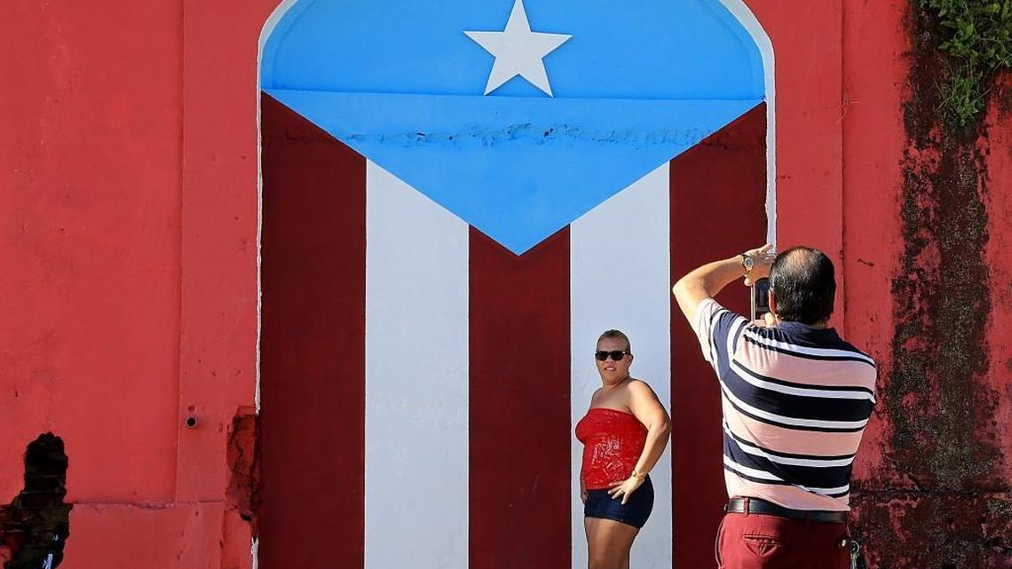 Visitors take a picture in Playa Punta Santiago in Humacao, Puerto Rico on Nov. 30, 2017. Most tourist areas on the island are open again for visitors, but in other areas, Hurricane Maria’s fury is still visible in damaged homes.