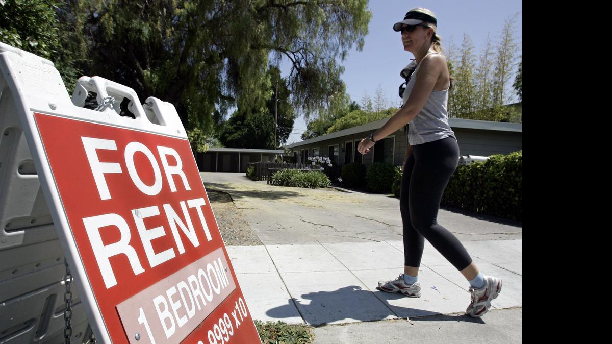 
A woman walks next to a "For Rent" sign at an apartment complex in Palo Alto, Calif., in 2006. A new analysis of Census data shows that 25 percent of U.S. renters have to use half their income or more to pay housing costs. 
