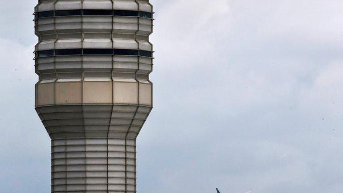 
An airplane flies past the air traffic control tower at Washington's Ronald Reagan National Airport, Monday, Aug. 10, 2015. In 2011, two airliners landed at Reagan National late at night without assistance from the airport’s control tower where the lone controller on duty had fallen asleep.
