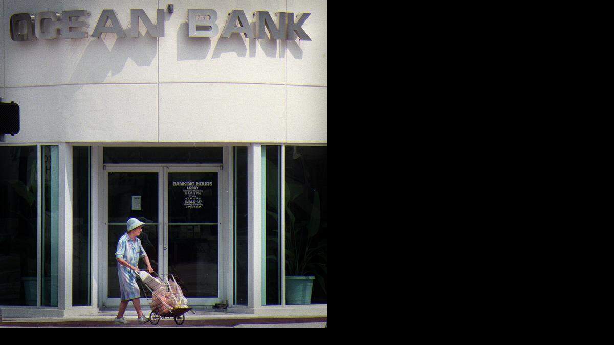 
A woman walks by the entrance of an Ocean Bank in Miami Beach in this file photo.
