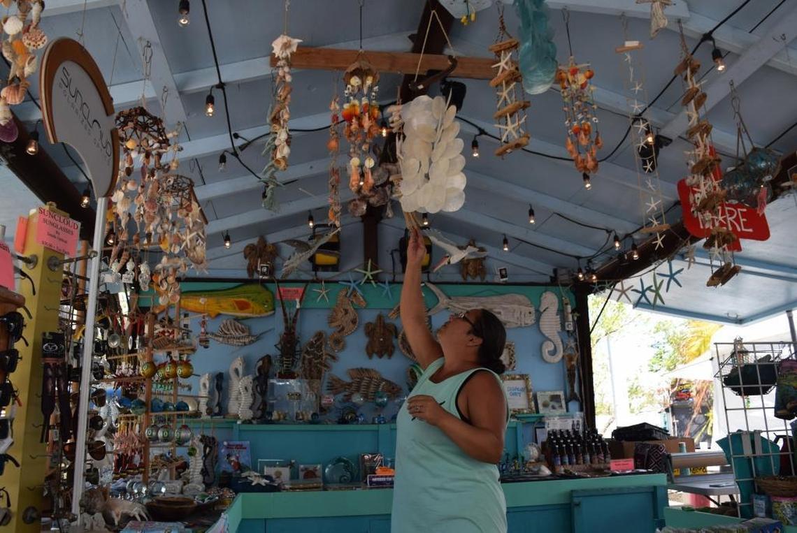 Viviana De Toro, a saleswoman, adjusts souvenirs at the Glass Shop, one of several gift shops at Robbie’s in Islamorada, on Oct. 4. The restaurant complex reopened in late September after rebuilding its dock.