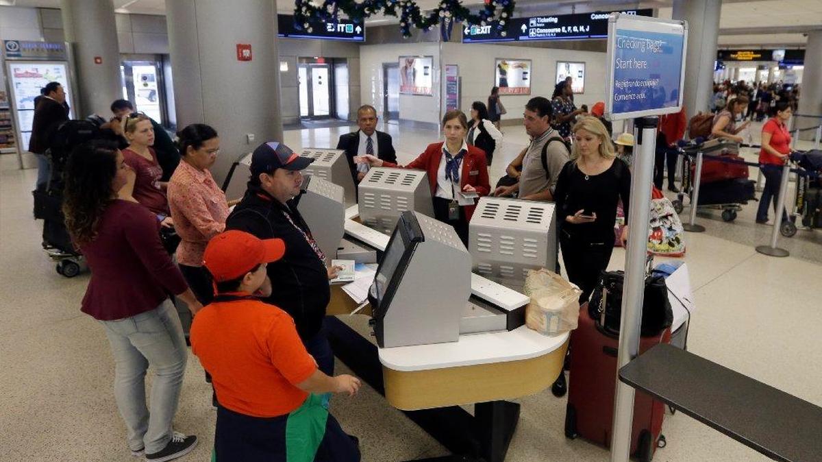 In this Nov. 25, 2014 file photo, travelers check in their luggage as they prepare to travel at Miami International Airport in Miami. A stronger economy and lower gas prices means Thanksgiving travelers can expect more highway congestion in 2015. Airlines for America, the lobbying group for several major airlines, forecasts 25.3 million passengers will fly on U.S. airlines, up 3 percent from last year.