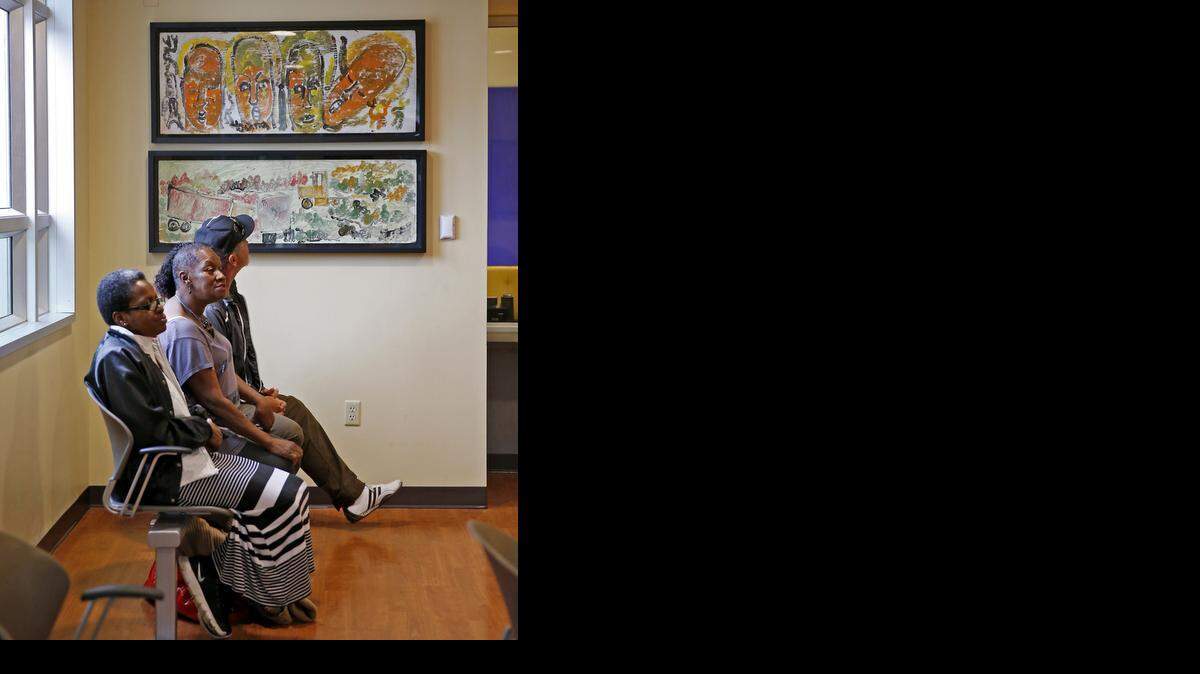 
Two of Purvis Young’s pieces hang in the waiting area of Camillus House, the Miami homeless shelter, on Nov. 21, 2014. Seated are clients, left to right, Rhonda Dixon, Rhoda Mae Lopez and Antonio Frontela.
