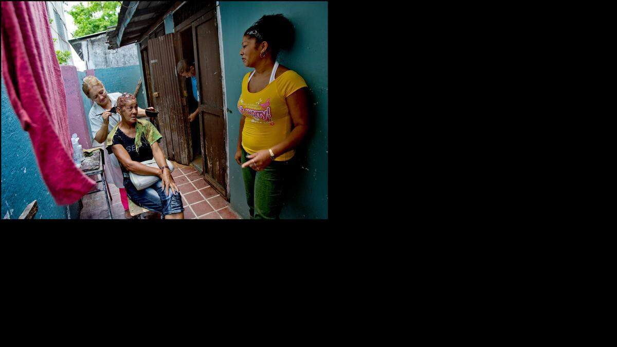 
Denia Ojeda Oliva does Maria Elena Matos Rivera's hair on Wednesday March 28, 2012 at Peluqueria Ibis in Santiago de Cuba. Oliva's husband (background) tries to repair a door as Rivera chats with her daughter. Under new rules announced Wednesday, U.S. exports of beauty supplies like nail polish and hair dye that support self-employed beauticians will be allowed.

