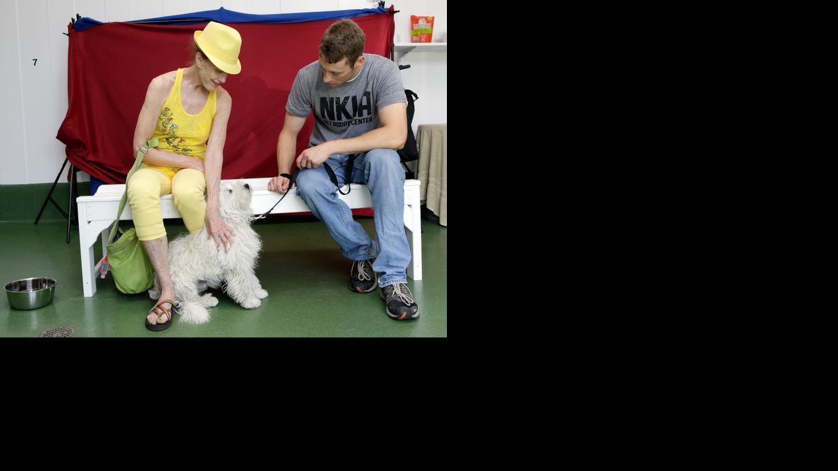 Sharon Lawler, from Playa Del Rey, Calif., left, with “Peluche,” a Tibetan-Terrier Mix available for adoption held by pet care giver Sean McGinnis, at the NKLA Pet Adoption Center in Los Angeles in 2013.