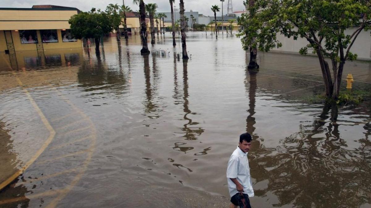 An identified man makes his way across the plaza in knee-high storm water. Hunter Plaza in Homestead, Florida is flooded due to the rains from Hurricane Katrina. Many storefronts were badly damaged by the intrusion of storm water.