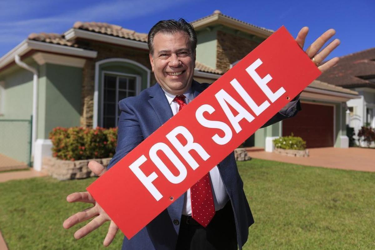 George C. Jalil, president of First Service Realty, holds a “for sale” sign in front of a home on Jan. 30. The house has many offers as home inventory is low and demand is high.