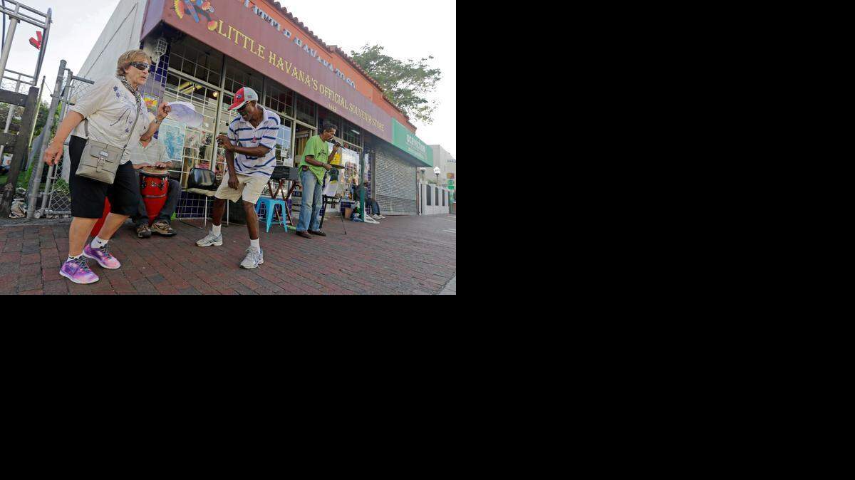 
Tourist Maureen Shutt, left, of Yorkshire, England, has fun as she dances with Luis Zelie, as a trio of friends play Cuban music on the sidewalk in the Little Havana area of Miami in this 2014 file photo. 
