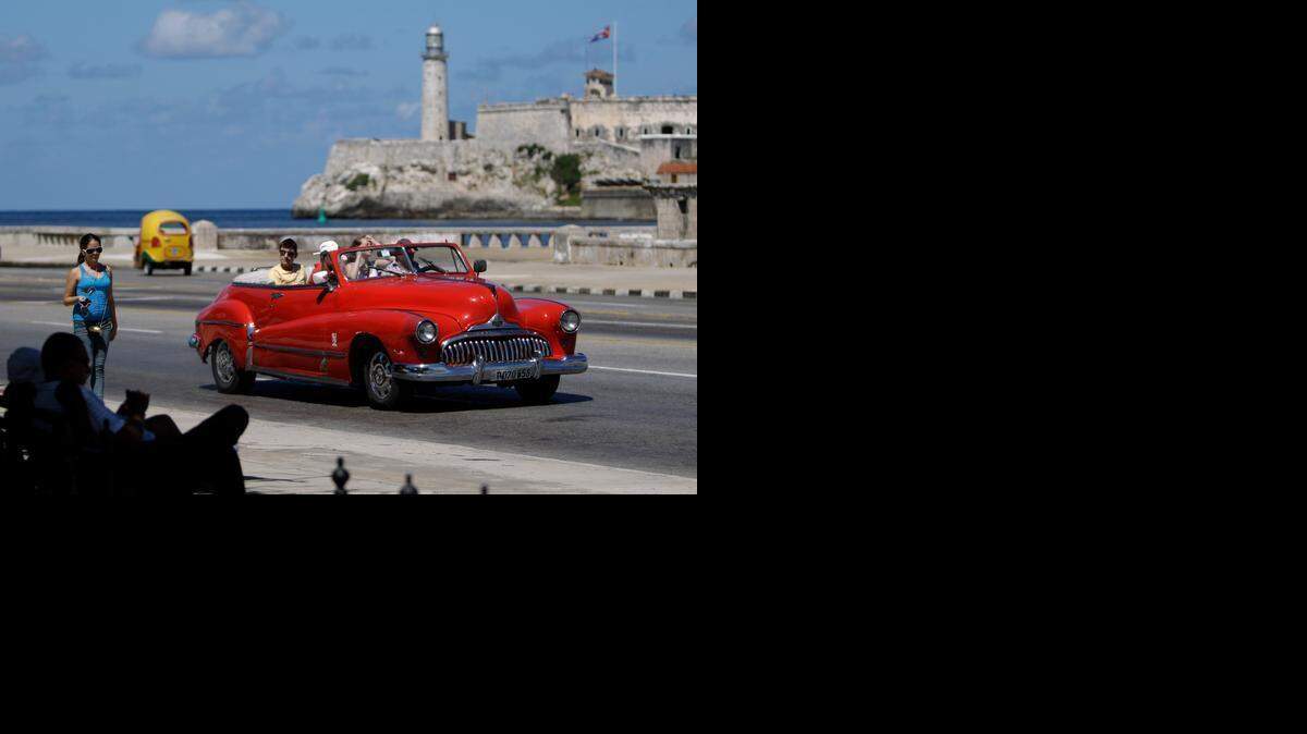 
FILE - In this Oct 12, 2013 file photo, tourists ride in a classic American car on the Malecon in Havana, Cuba. A new set of U.S. government regulations takes effect Friday, Jan. 16, 2015, severely loosening the 50-decade long travel and trade restrictions for Cuba. 
