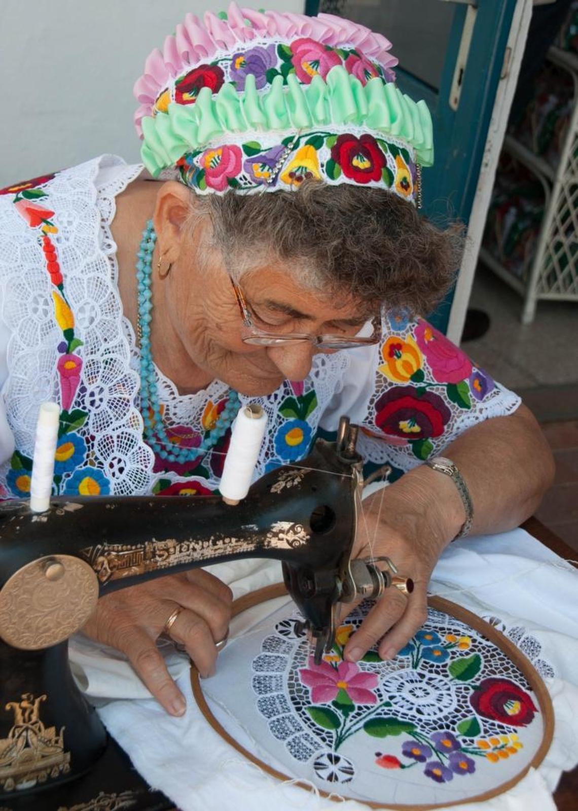 A woman stitches traditional embroidery on a foot-pump sewing machine in Kalocza, Hungary, 2016.