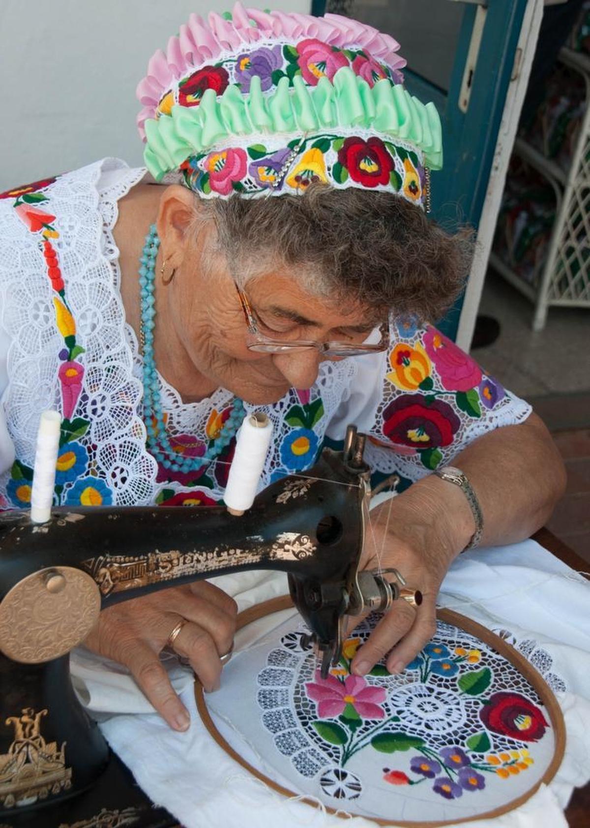 A woman stitches traditional embroidery on a foot-pump sewing machine in Kalocza, Hungary, 2016.