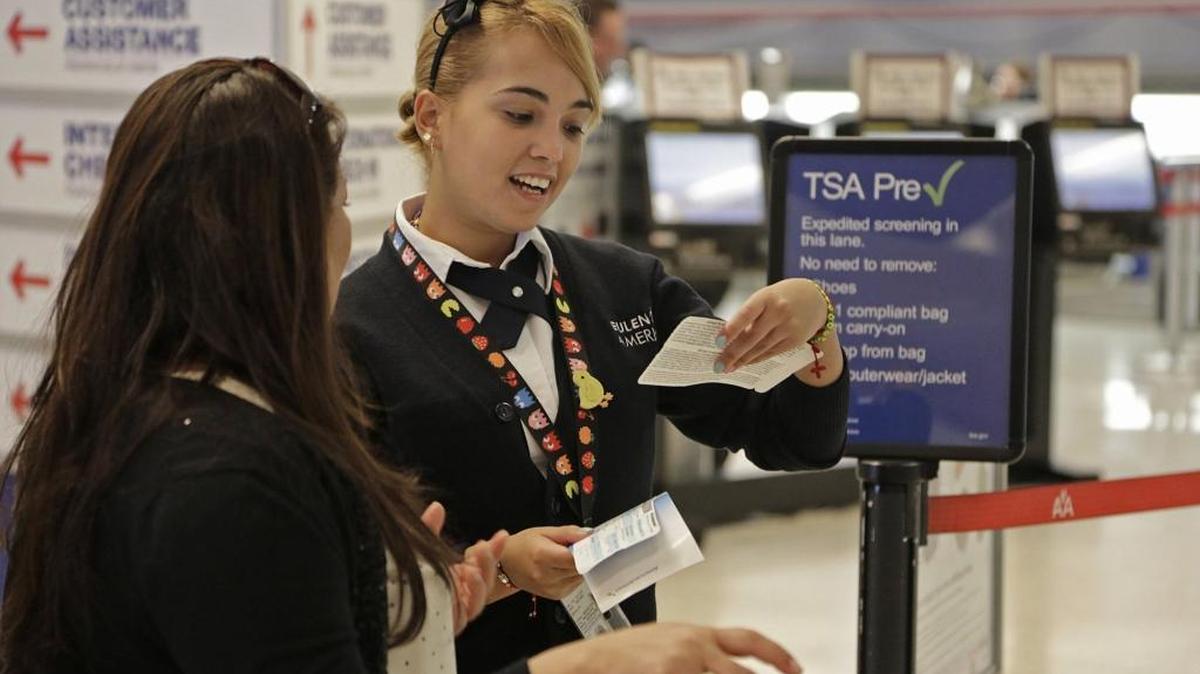 Syndy Perez, right, helps a traveler make her way through TSA Pre-Check at Concourse D during the Thanksgiving holiday week in November 2013 at Miami International Airport.