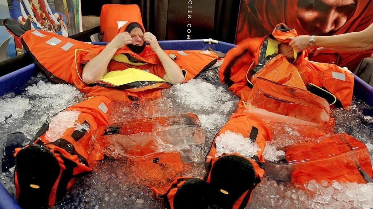 Alex Bernt, left, and John Sifling, right, of White Glacier, a marine company that produces survival thermal wear, adjust the hoods on their suits while floating in a pool of icy water for more than two hours as part of a demonstration of the survival gear. On Tuesday, the cruise industry's largest annual conference, Seatrade Cruise Gobal, was held at the Greater Fort Lauderdale/Broward County Convention Center.
