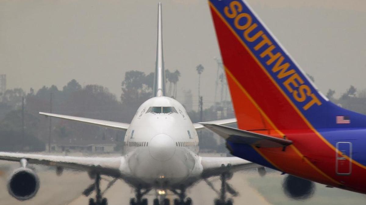 A jet taxies as a Southwest Airlines jet takes off at Los Angeles International Airport.