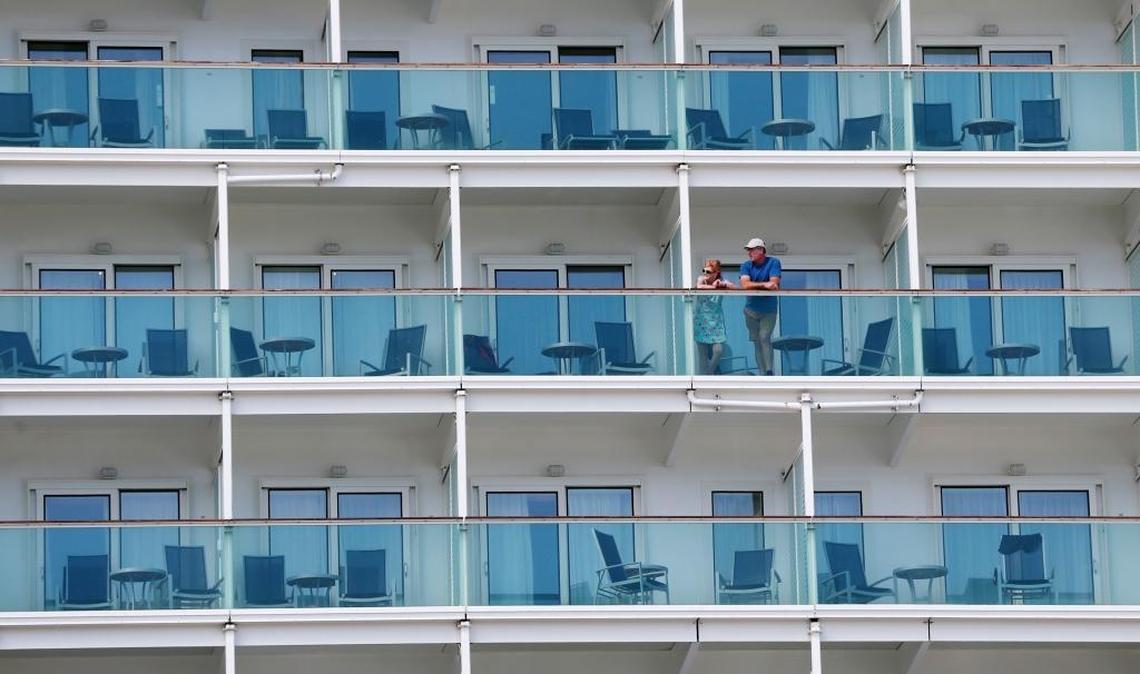 A pair of passengers aboard the Royal Caribbean International cruise ship Liberty of the Seas look from their balcony as other passengers disembark, Tuesday, Aug. 29, 2017, at PortMiami in Miami. The Galveston, Texas-based cruise ship was scheduled to return to the city Sunday but was diverted to Miami, because of Hurricane Harvey.