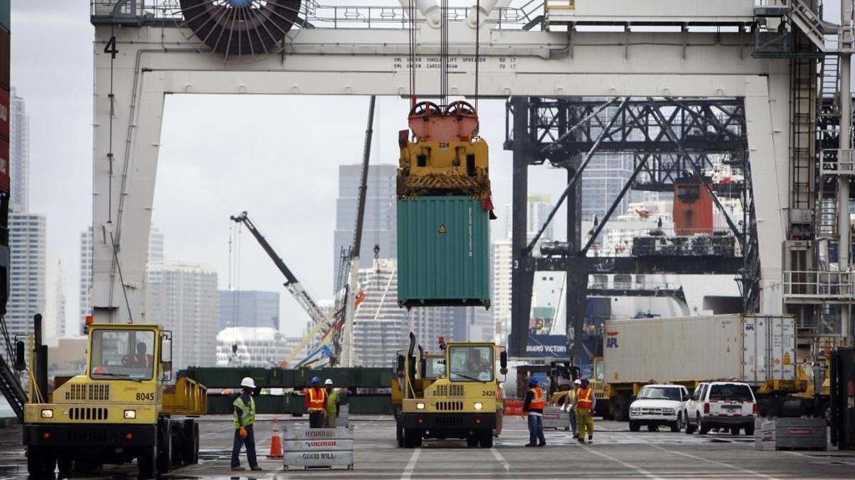 Workers on the docks load cargo off of a ship and onto a truck at the Port of Miami.