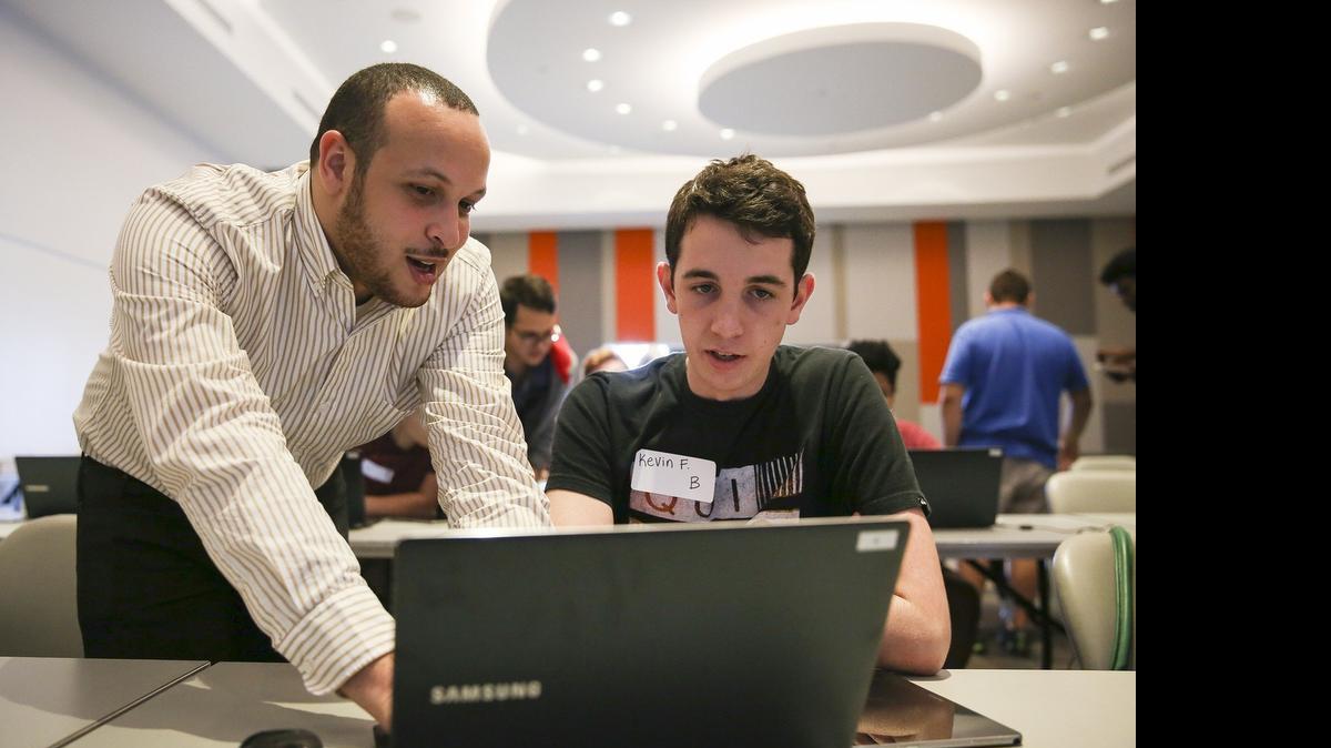 
Instructor Daniel Taveras, 27, helps Kevin Fitzpatrick, 17, of Archbishop McCarthy High School, create an app at the Samsung Mobile App Academy at the University of Miami on Thursday. Fitzpatrick is one of 60 South Florida high school students selected to attend the weeklong academy. He is building a CPR assistant app that will help regular citizens decide the best steps in an emergency situation. Fitzpatrick thought of the idea after recently becoming CPR certified.
