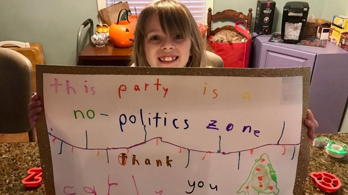 Eight-year-old Carly Barr holds the sign she made at her mom Jennifer’s suggestion, banning political discussions at their Christmas kickoff party. It worked!