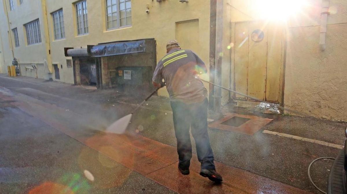 Miami Beach worker Melvin Gaitan uses a pressure cleaner to spray hot water in an effort to combat mosquitoes. Officials say the beach’s tall buildings and round-the-clock action make it harder to apply aerial pesticides.