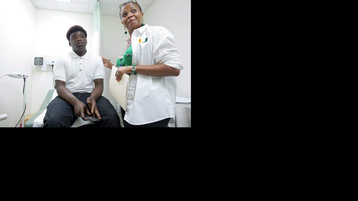 
Dr. Marie-Denise Gervais talks to Amos LeClerc as she performs an examination on him at a clinic in a Miami high school this summer. More than 50 percent of Medicaid recipients in Florida are under the age of 18, according to state officials.
