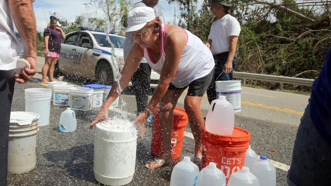 In this Oct. 5, 2017, photo, people collect water from a creek flowing down the mountains on a road in Puerto Rico, after Hurricane Maria lashed the island on Sept. 20. In Florida, state officials anticipate a wave of migrants displaced by hurricanes in Puerto Rico and the U.S. Virgin Islands, and healthcare workers have been advised to watch for post-storm health risks among evacuees.